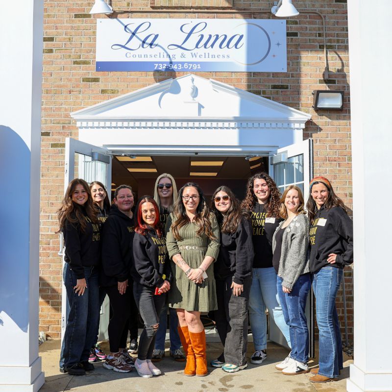 Group standing outside La Luna storefront entrance, smiling in front of the sign.