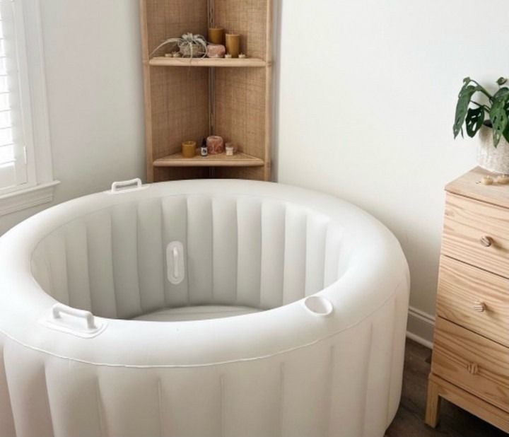 White inflatable baby playpen in a bright nursery beside a wooden shelf and dresser