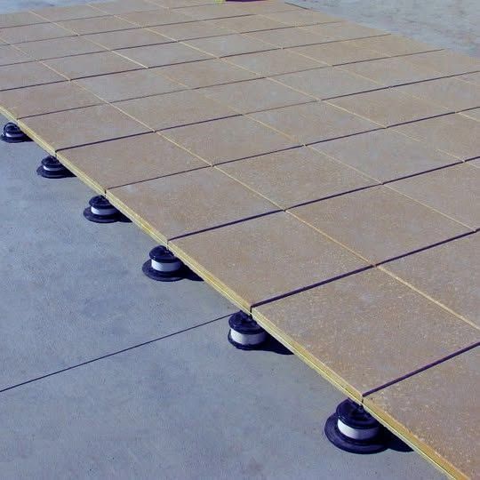 Raised platform with tan panels on black supports over a gray floor