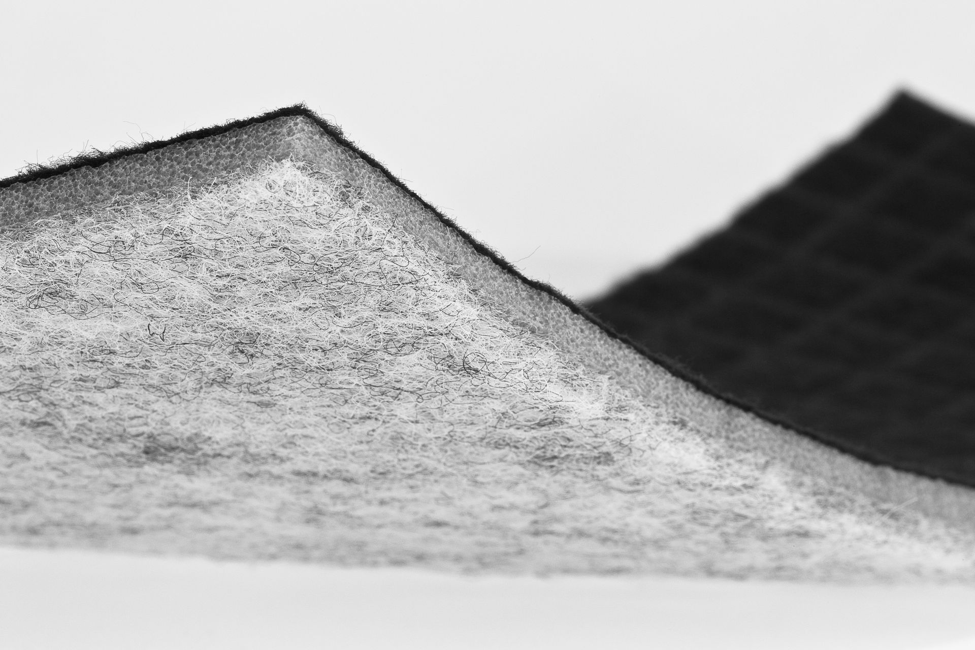 Close-up of a gray, textured mound against a white background with a dark diagonal shape behind it