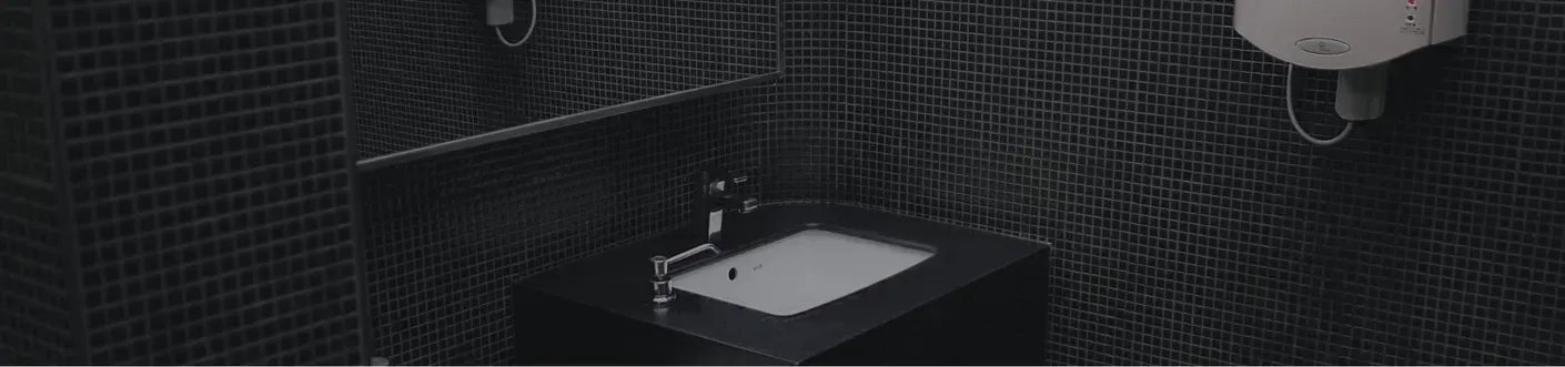 Black bathroom with tiled walls, a white sink, and a toilet under a wall-mounted tank.