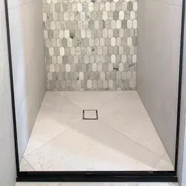 Empty tiled shower with a square drain and mosaic accent wall