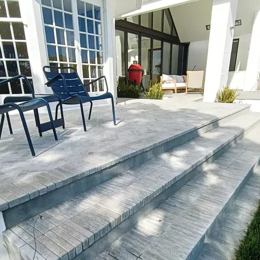 Modern patio with blue chairs, tiled steps, and glass doors outside a white building