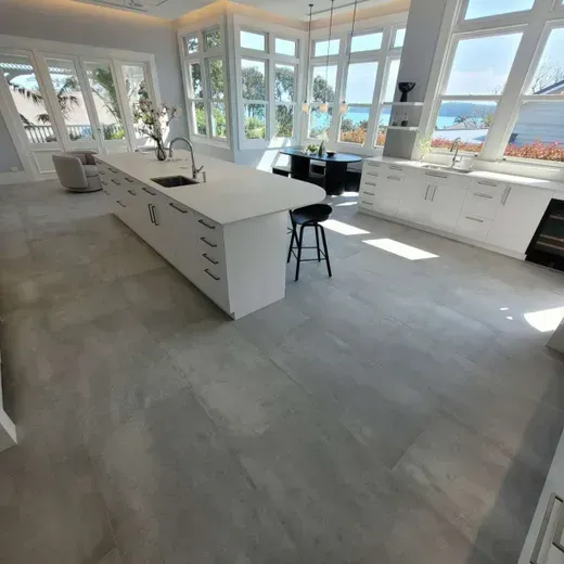 Bright modern kitchen with white cabinets, large island, and ocean-view windows.