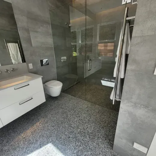 Modern gray bathroom with glass shower, floating vanity, and white toilet