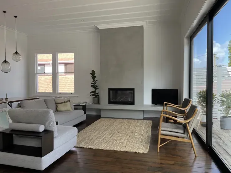 Bright modern living room with gray sofa, fireplace, rug, and large sliding glass door