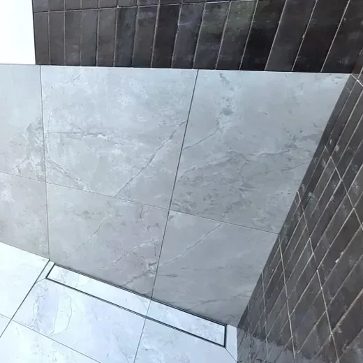 Modern tiled shower corner with gray wall tiles and dark accent tiles