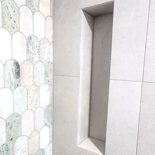 Vertical wall niche beside pastel scalloped tile on a light tiled surface