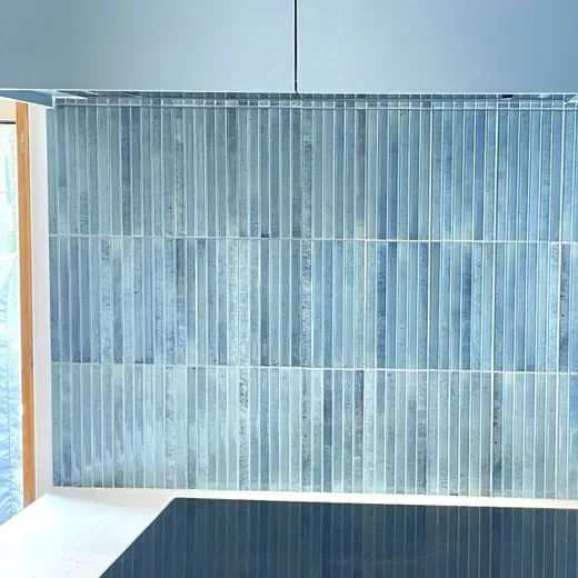 Blue striped wall paneling behind a white bench and dark table in a minimalist room