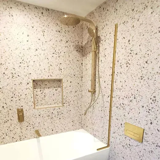 Bathroom with speckled wallpaper, a bathtub, showerhead, and built-in wall niches.