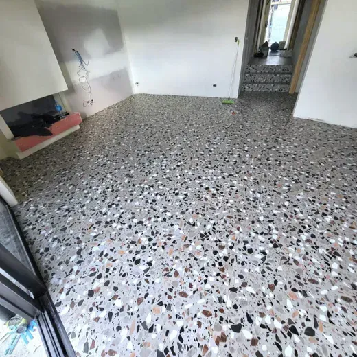 Terrazzo-floored room with white walls, a stairway, and an open door to another area.