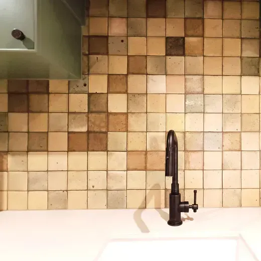 Kitchen sink with black faucet against a beige tiled backsplash.