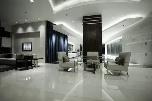 Modern minimalist hotel lobby with white glossy floors, dark columns, and cream lounge chairs