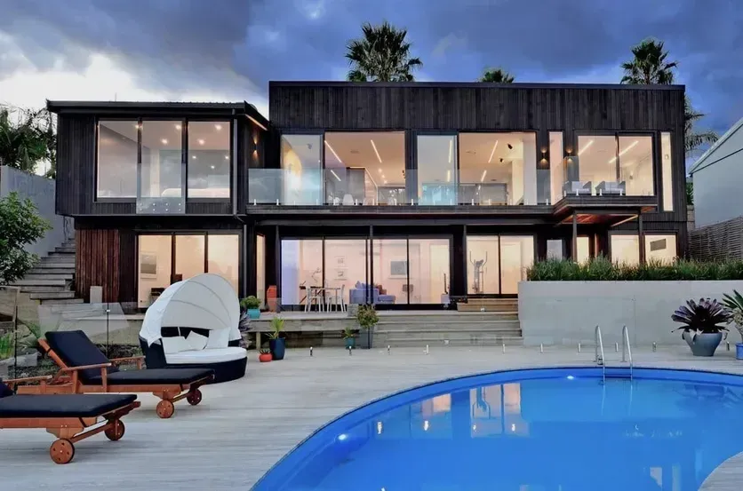 Modern two-story house with large windows and pool at dusk