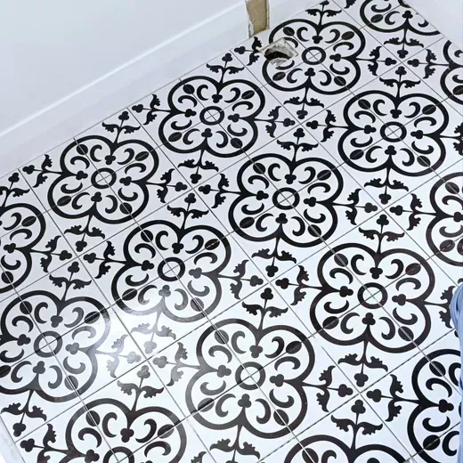 Black-and-white patterned floor tiles in a corner of a room with a white wall