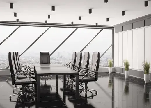 Modern conference room with long table, black chairs, and large windows overlooking water