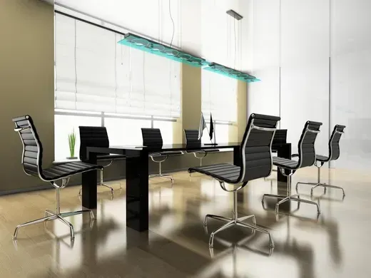 Modern glass conference room with black chairs and a long table by large windows