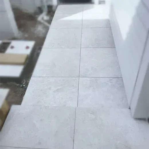 White tiled balcony walkway beside a building, viewed from above