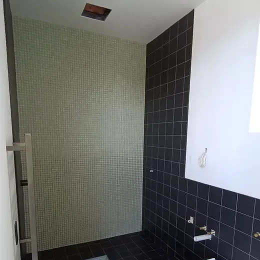Empty tiled bathroom with black and light green walls and a window on the right