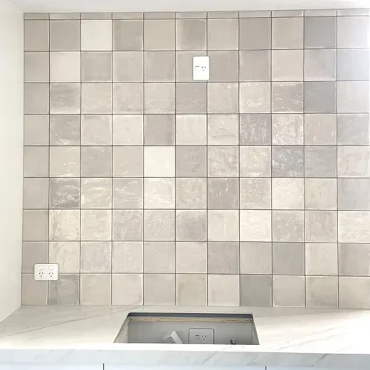 Empty tiled shower wall with a recessed niche and floor drain.