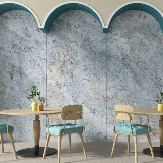 Two teal chairs and a small wooden table against a textured gray wall with teal arches above.