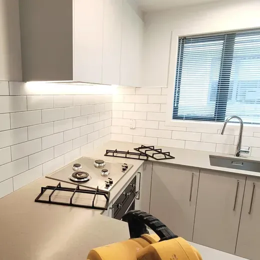 Modern white kitchen with gas stove, subway tile backsplash, and window above the sink