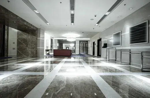 Bright modern lobby with marble floors, white walls, and a red bench in the distance