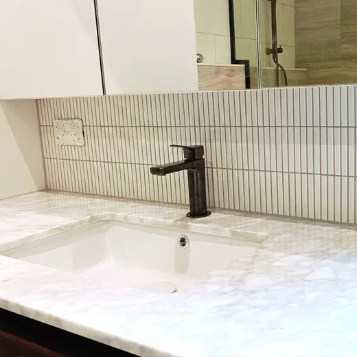 Modern white bathroom vanity with a black faucet and rectangular mirror above a tiled backsplash