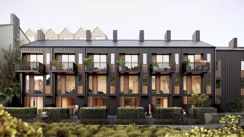 Modern two-story townhouse facade with balconies, dark trim, and landscaped front hedges.