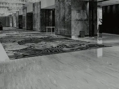 Empty hotel lobby with patterned carpet, marble columns, and polished floor in black and white.
