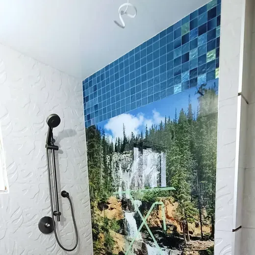 Bathroom shower with waterfall forest mural and blue tile accents