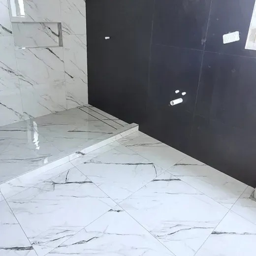 White marble-tiled floor and step beside a glossy black wall in a modern interior