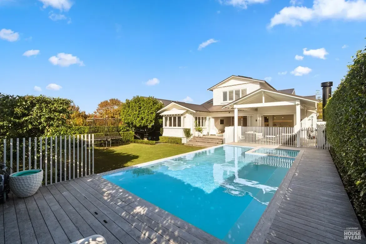 Modern house with a covered patio and a blue swimming pool in a backyard under a clear sky