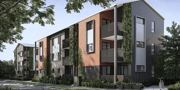 Modern apartment building with gray, white, and wood-paneled facades, surrounded by trees and landscaping