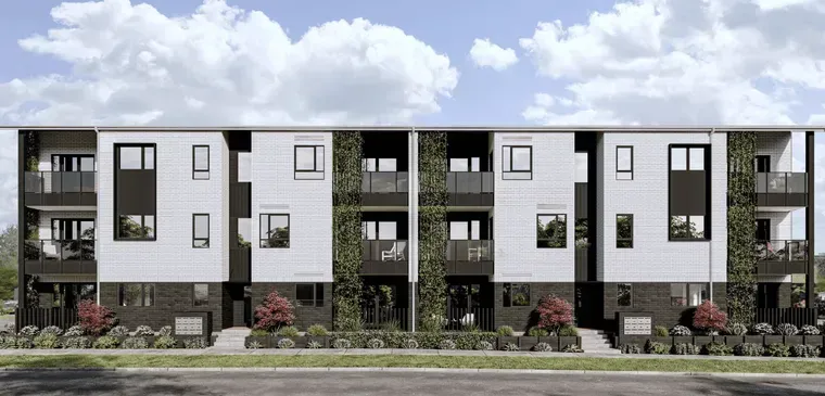 Modern apartment building facade with white and dark panels, balconies, and landscaped greenery