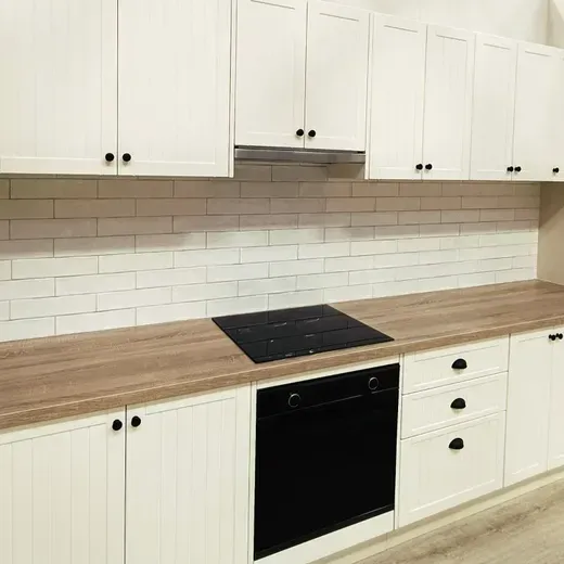 White kitchen with wood countertops, subway tile backsplash, and black oven.