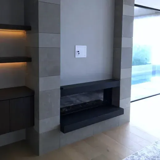 Modern living room corner with a gray built-in fireplace and sliding glass door.