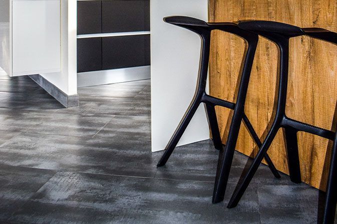 Modern kitchen with wood bar stools, black legs, and gray tiled floor.