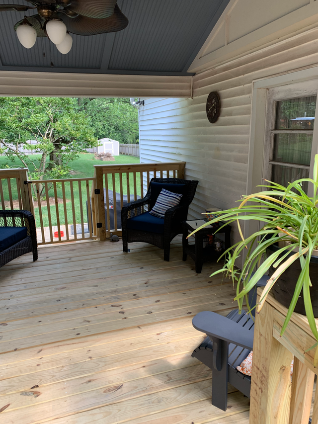 A porch with chairs and a ceiling fan.