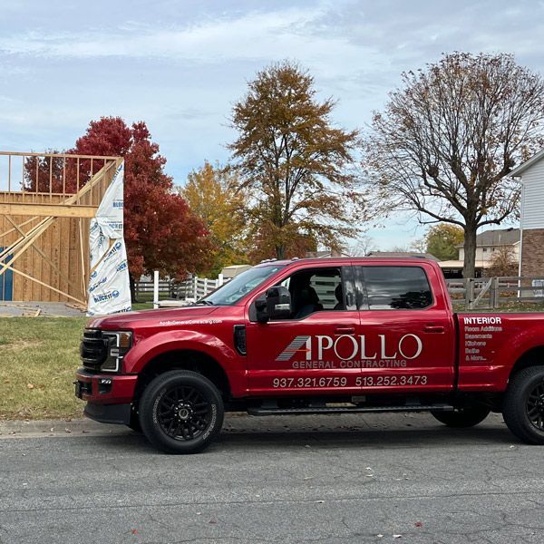 A red apollo truck is parked in front of a house under construction