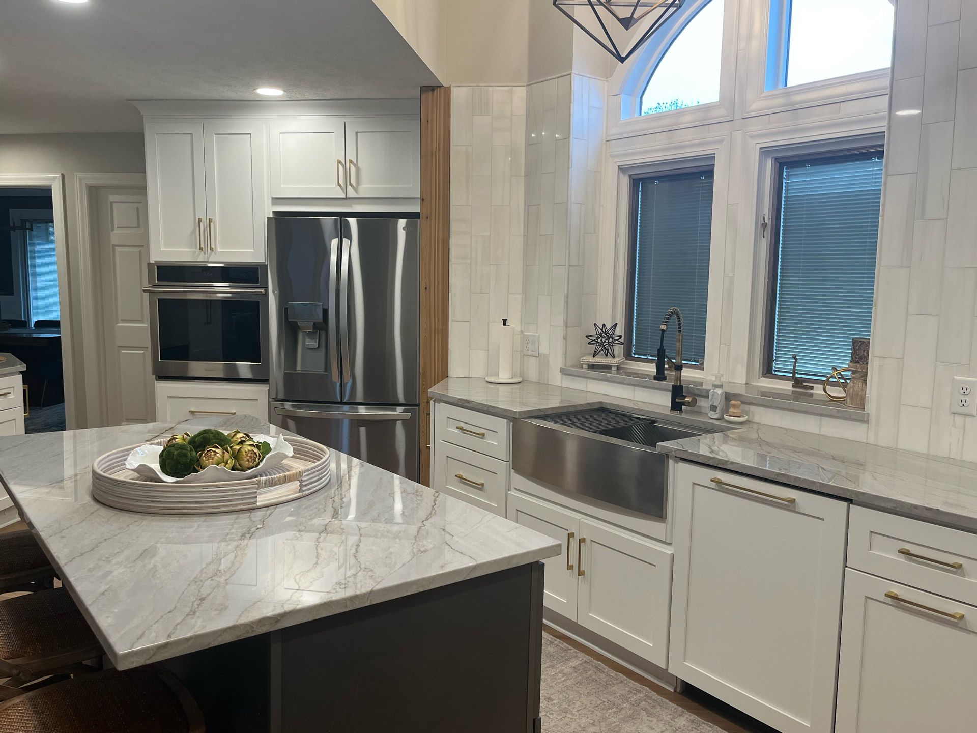 a kitchen with white cabinets , stainless steel appliances , a sink and a refrigerator .