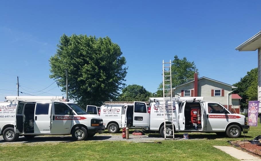 White utility vans parked in a row at a service site under a clear blue sky