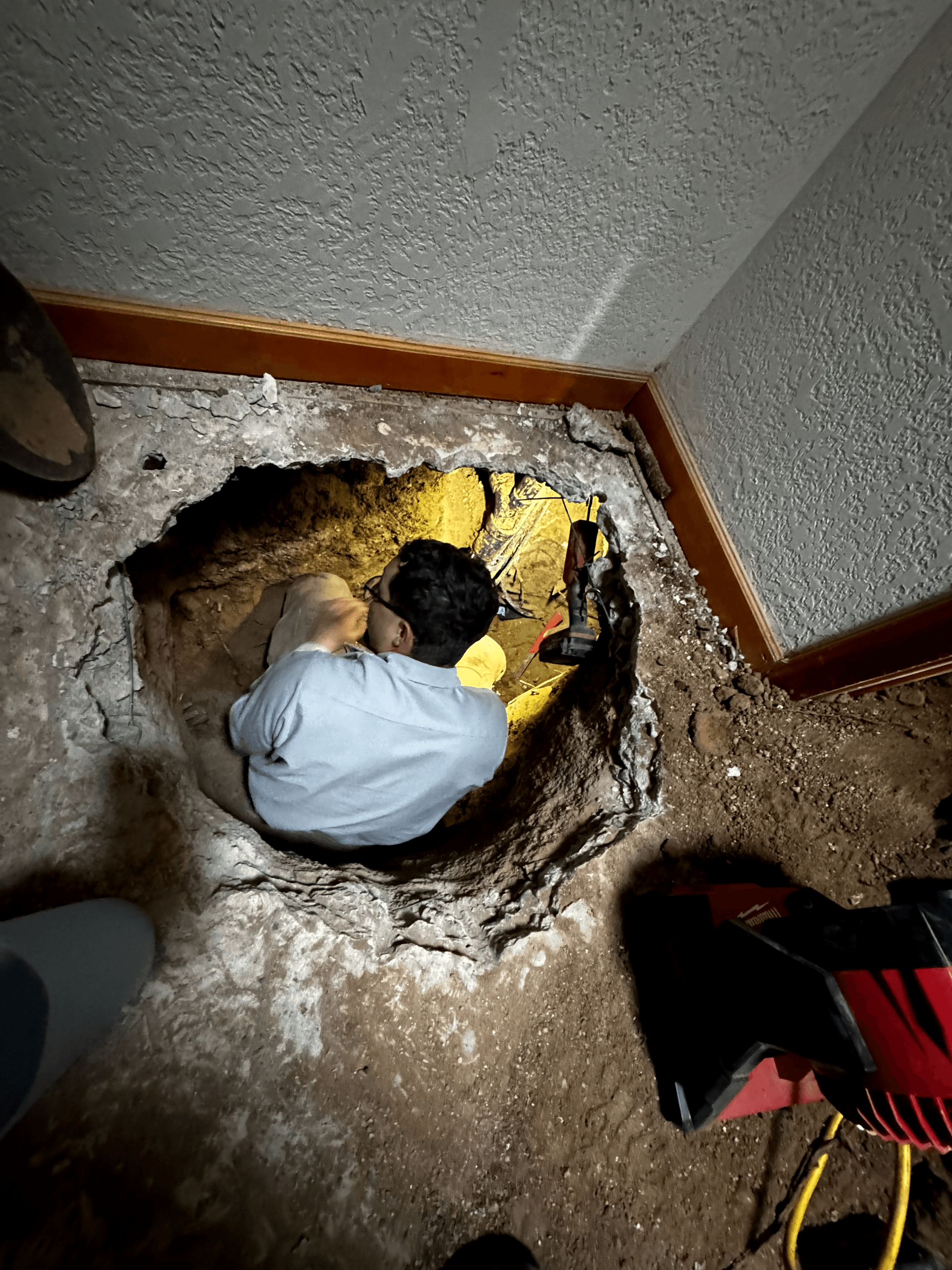 A man is sitting in a hole in the floor.