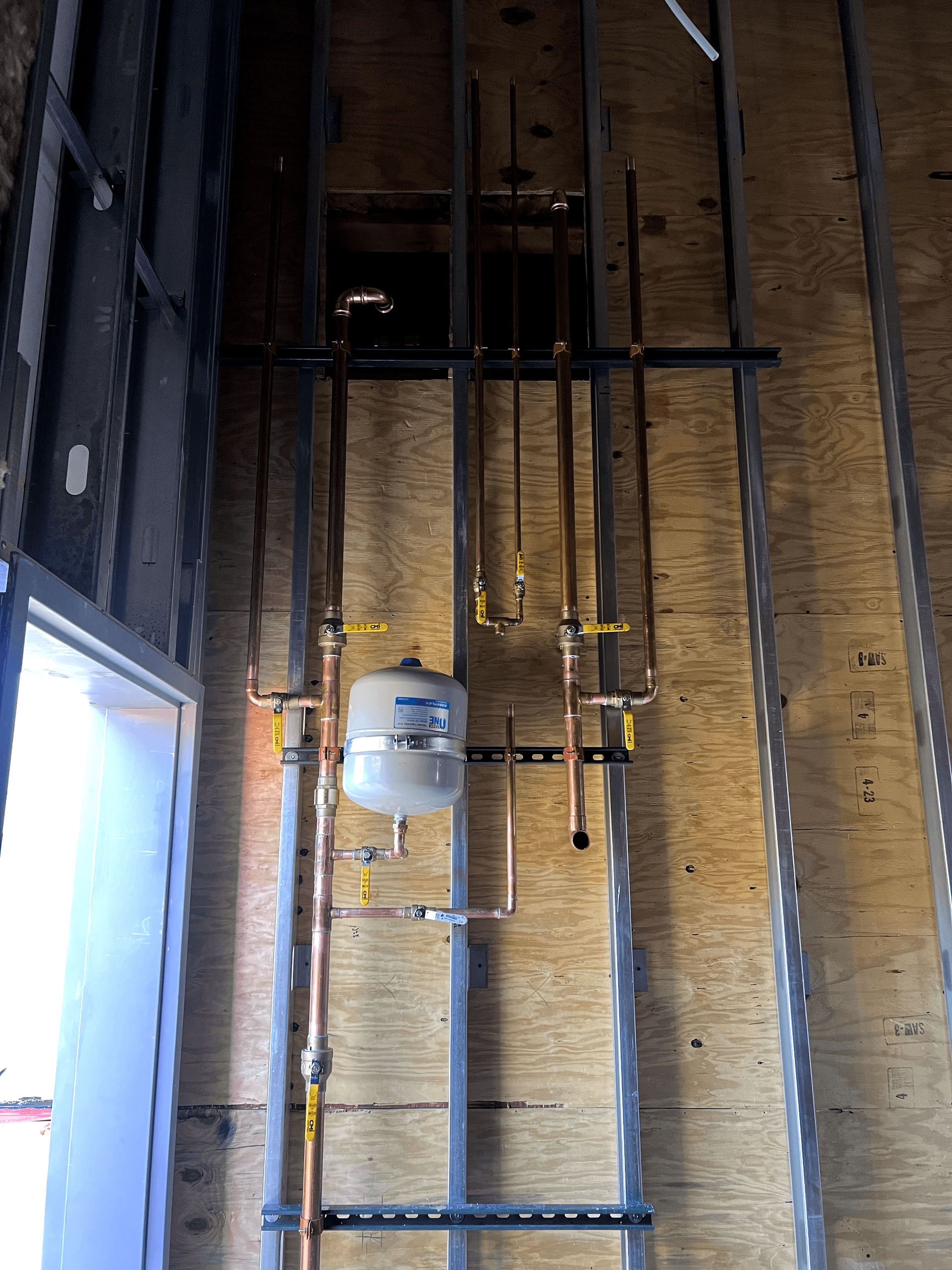 A wall with pipes and a tank hanging from it