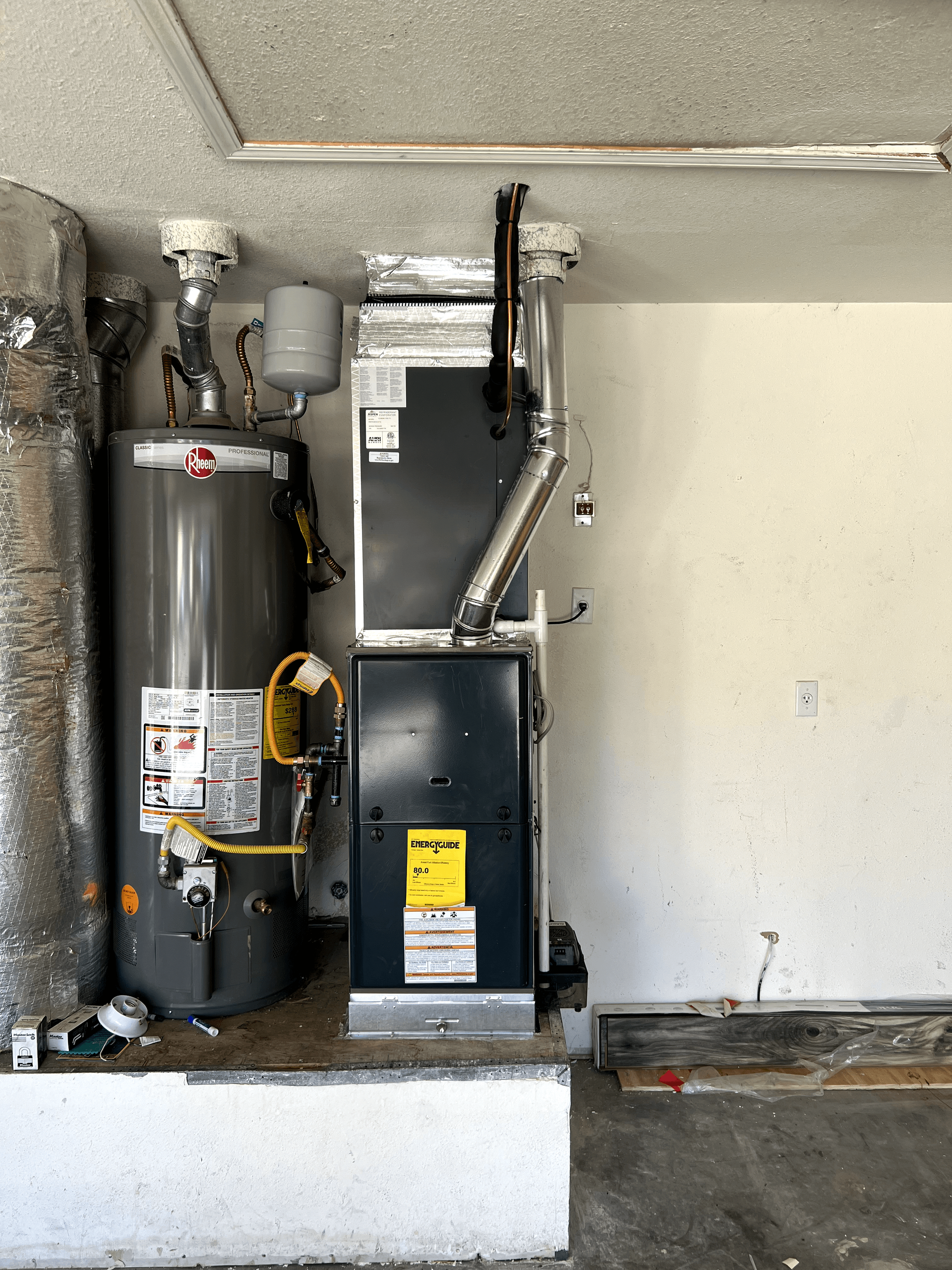 A water heater and a heating system are in a garage.