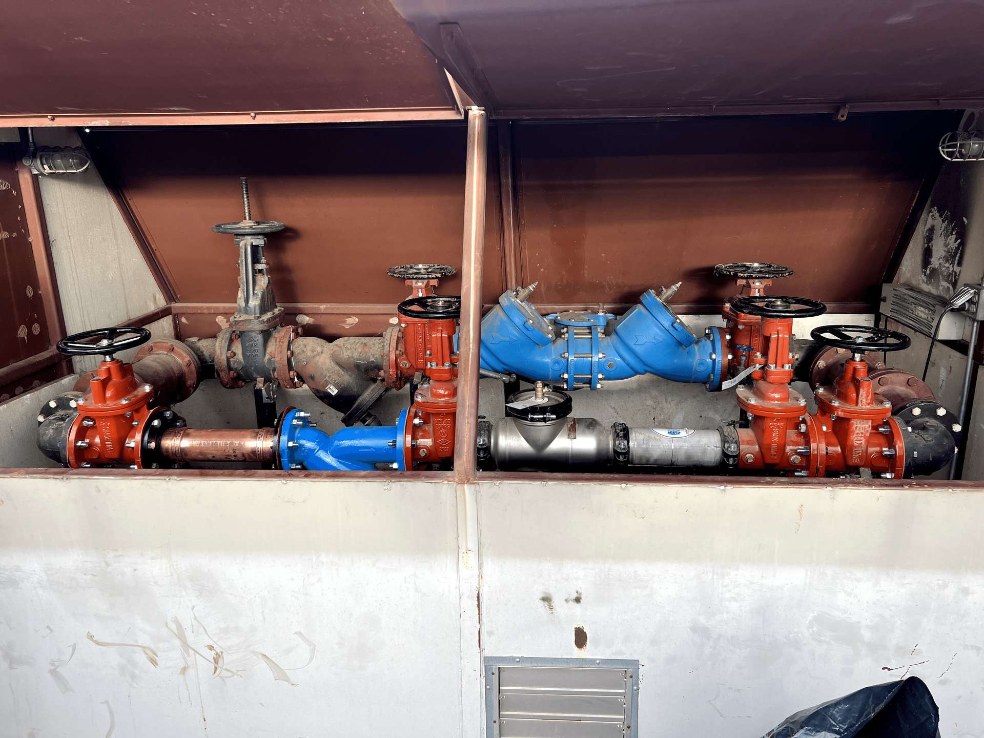A bunch of pipes and valves are in a box.