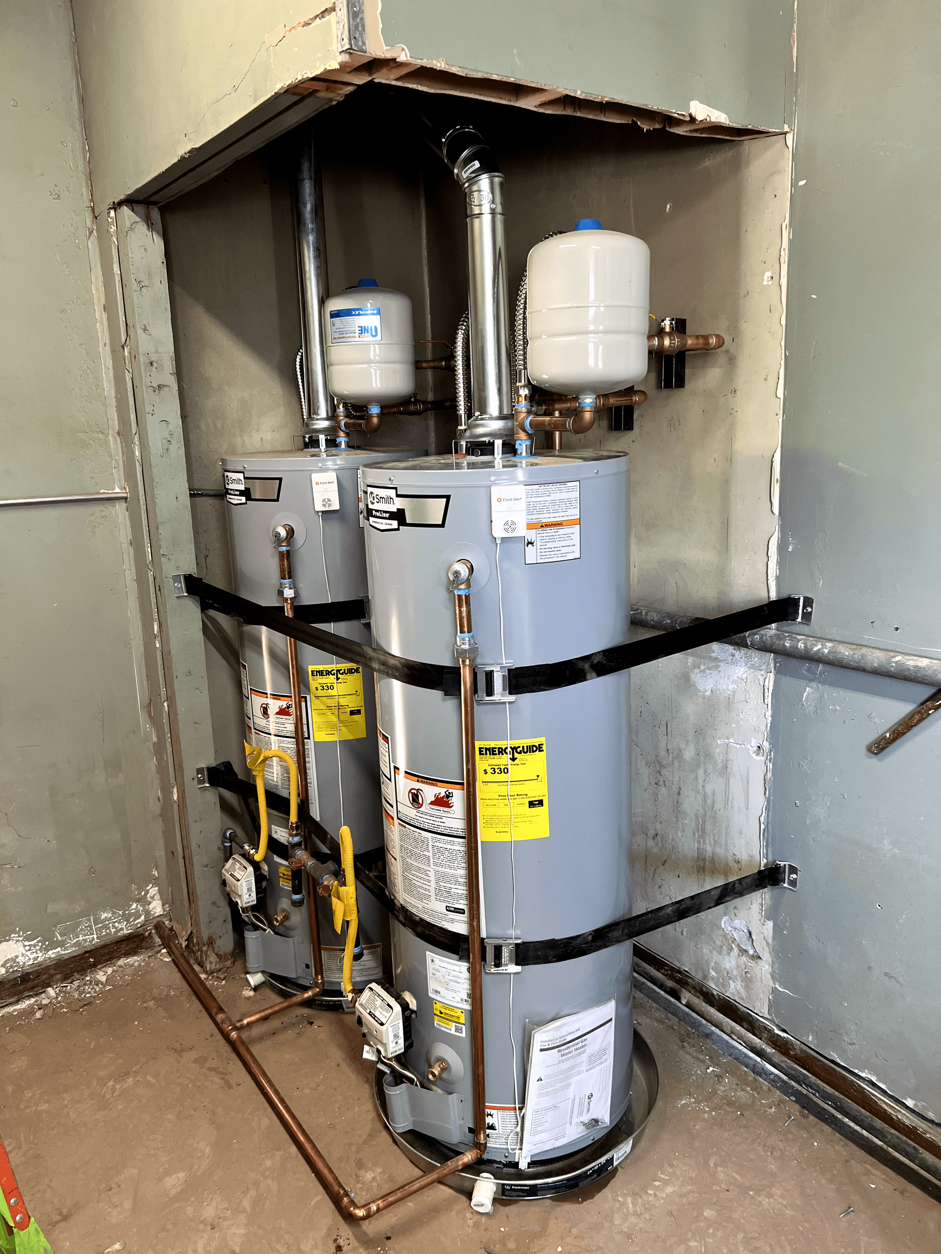 Three water heaters are sitting next to each other in a room.