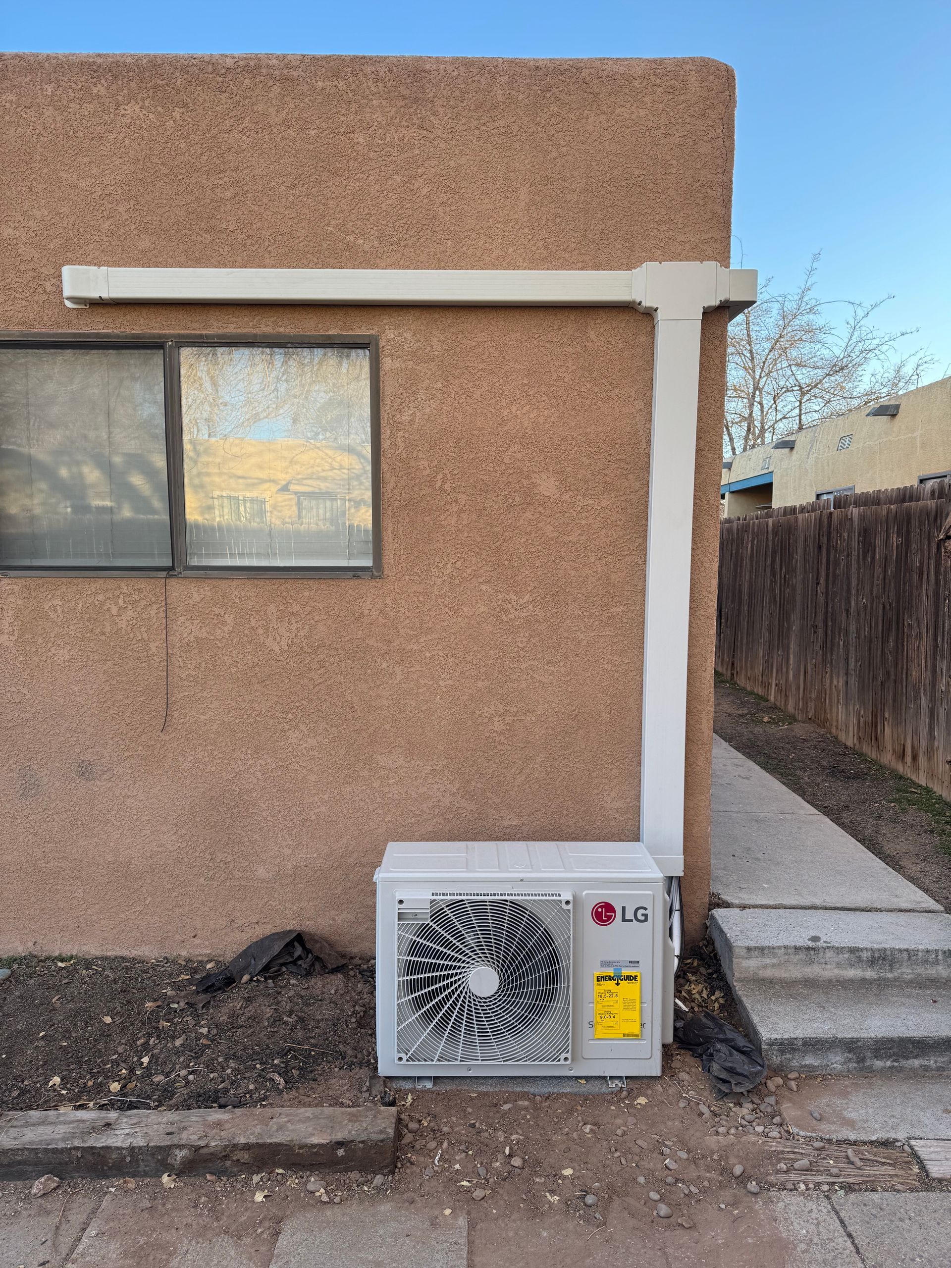 An lg air conditioner is installed on the side of a building next to a window.