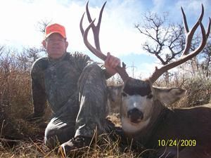 Hunter kneels next to a large deer with impressive antlers, both smiling in a field; date is 10/24/2009.