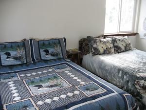 Two beds with nature-themed bedding in a room with a window.